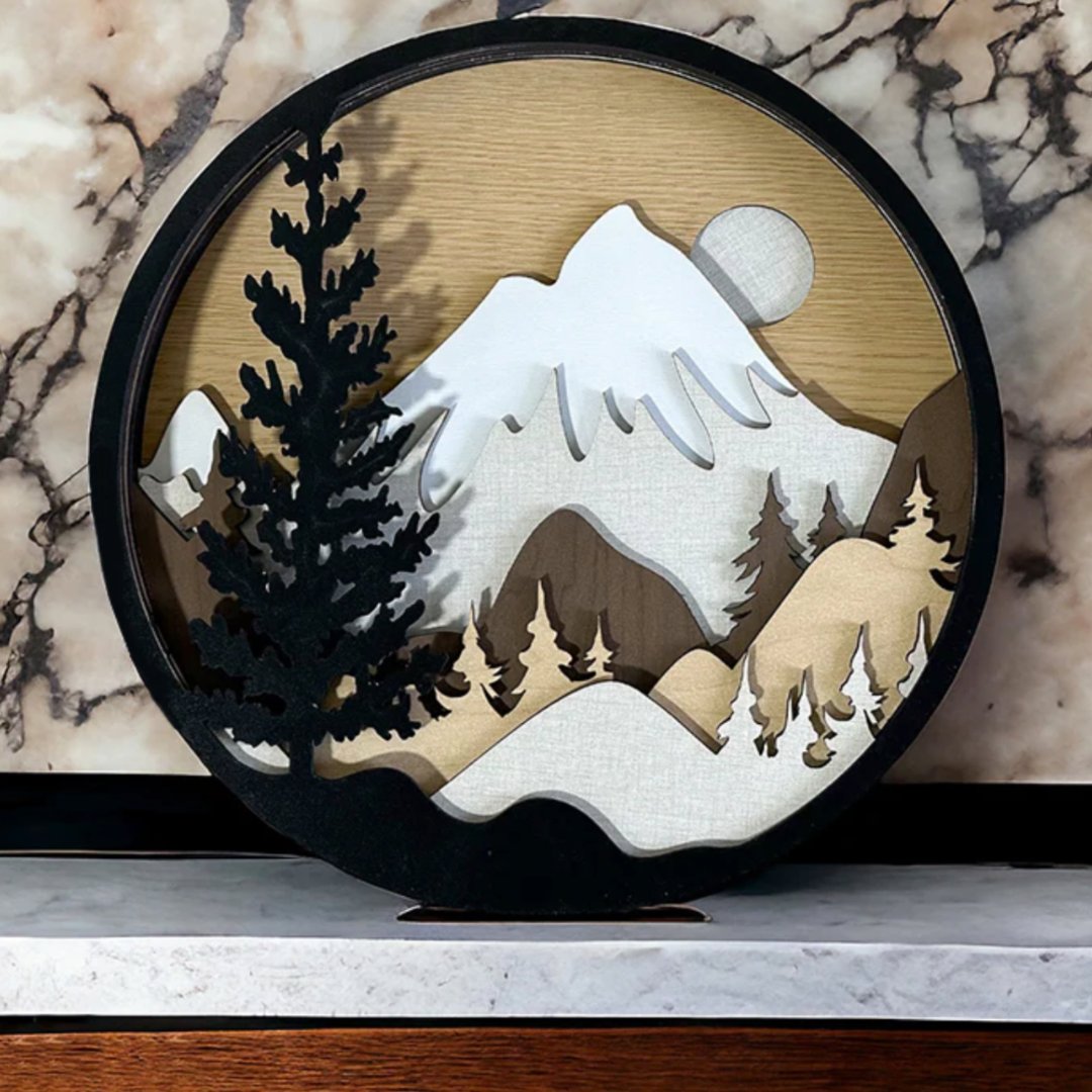 A circular sign with a mountain scene with trees made with Truflat wood on a laser cutter machine